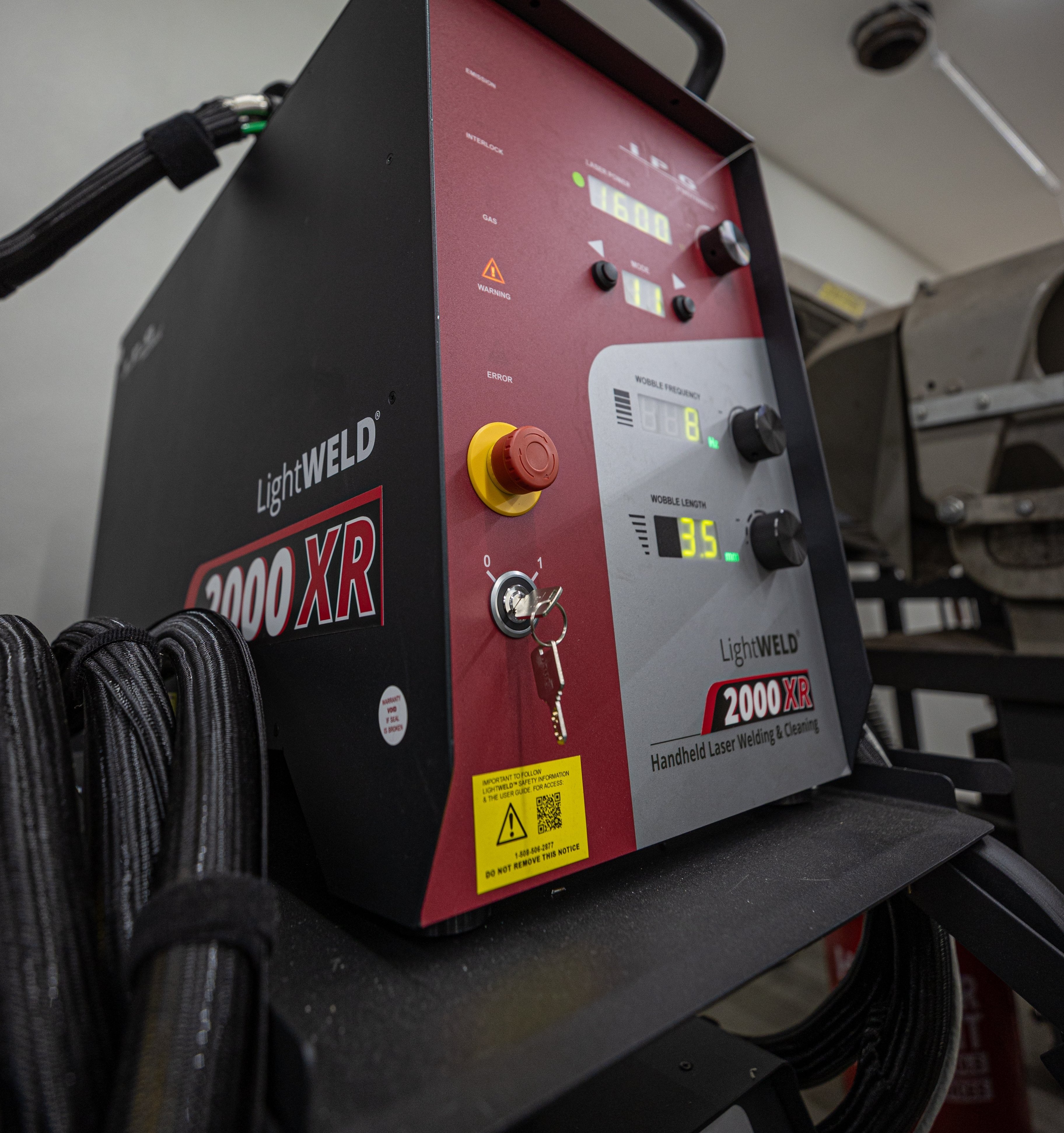 A welder welding two pieces of metal with a laser.