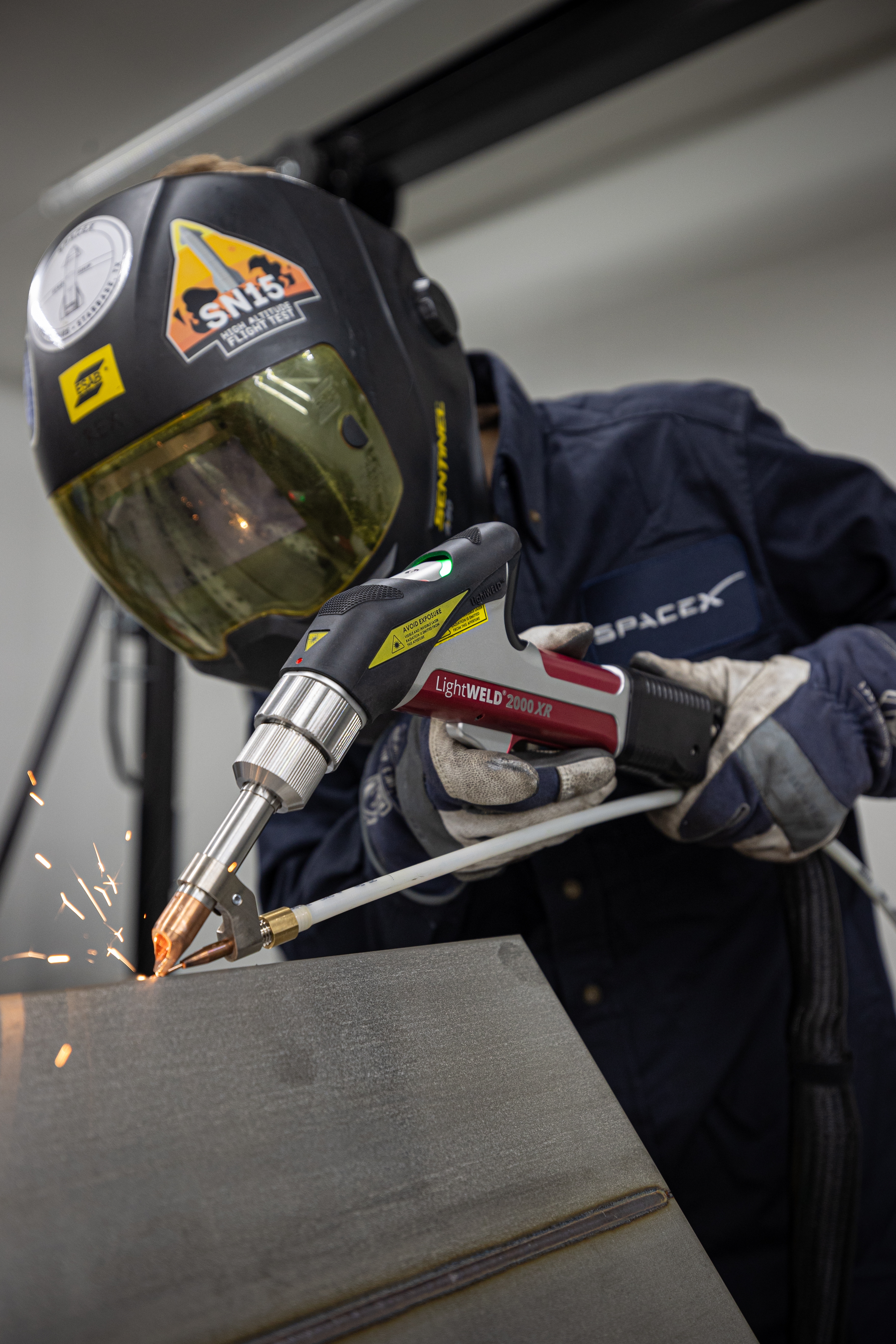 A welder welding using a handheld laser welder