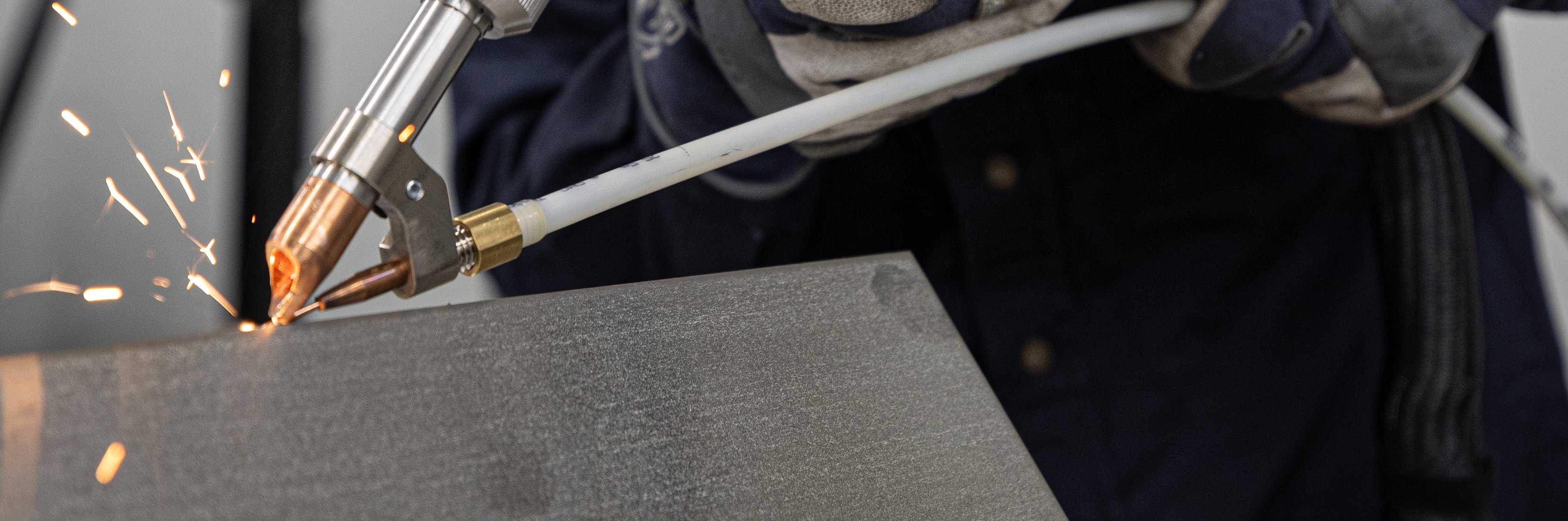 A welder welding two pieces of metal with a laser.