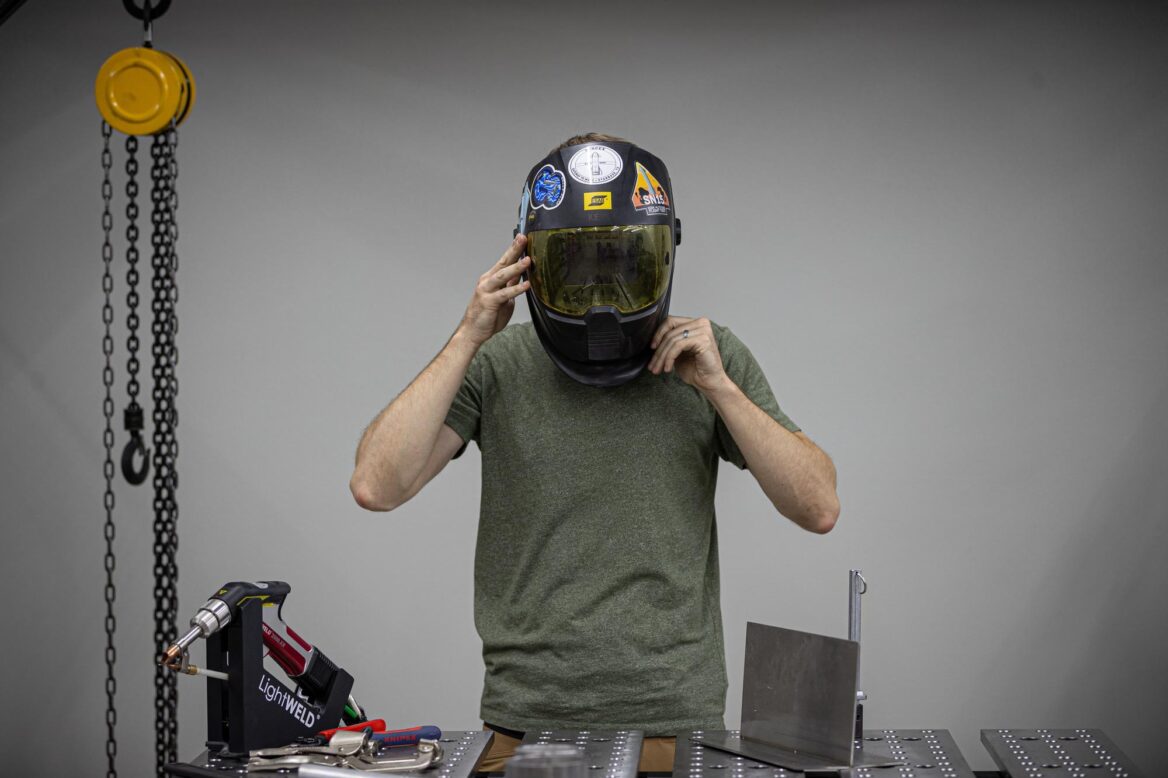 Welder putting on protective face mask.